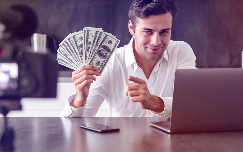 Man holding up cash shows how to make money on YouTube